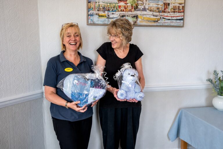 Staff members holding handmade memory keepsakes made for residents' families